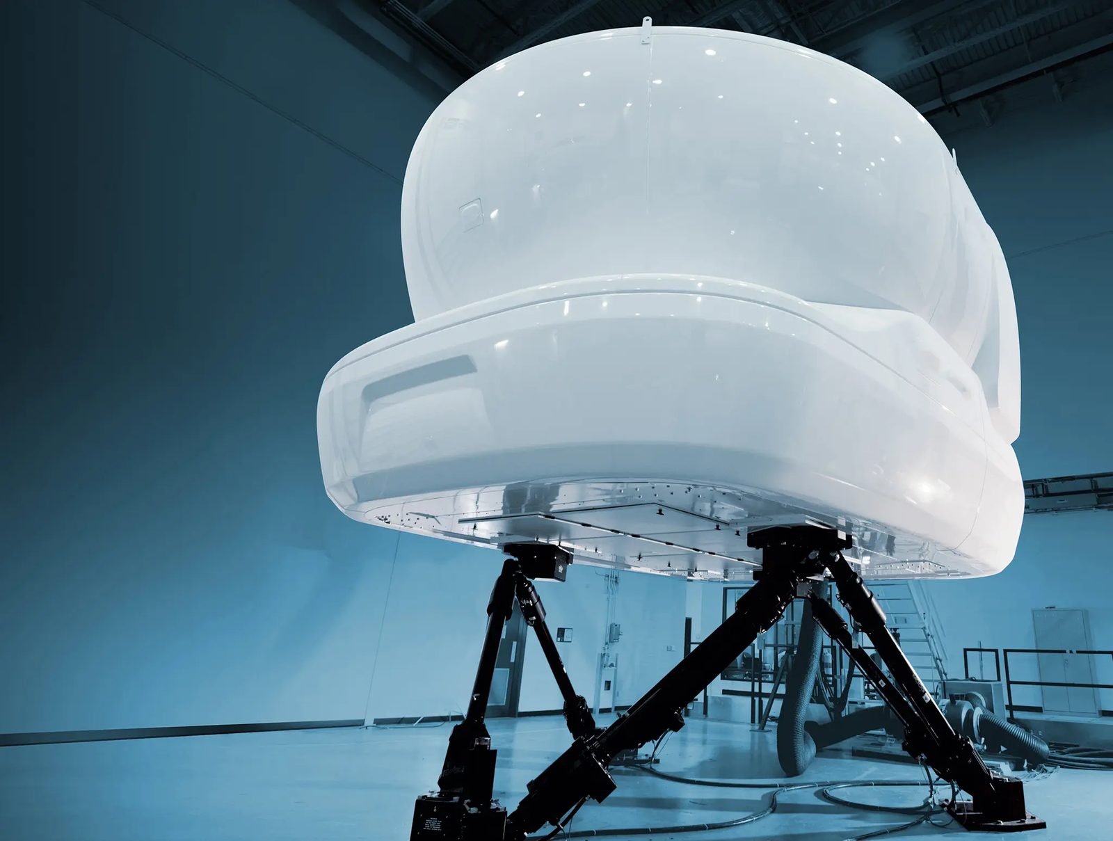 A full-flight simulator raised on its motion platform in a training bay.